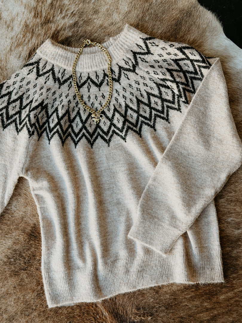 Beige sweater with black pattern on a fur surface