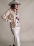 Woman in western boho outfit with cowboy hat, embroidered jacket, and satin skirt