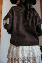 Woman in brown western sweater with white cow print details and layered lace skirt