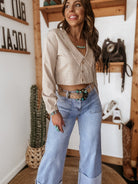 Woman wearing western boho outfit with cropped plaid blouse, wide-leg jeans, turquoise jewelry, and cowgirl accessories.