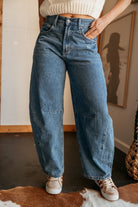 Woman wearing high-waisted wide leg denim jeans and cow print sneakers, western style