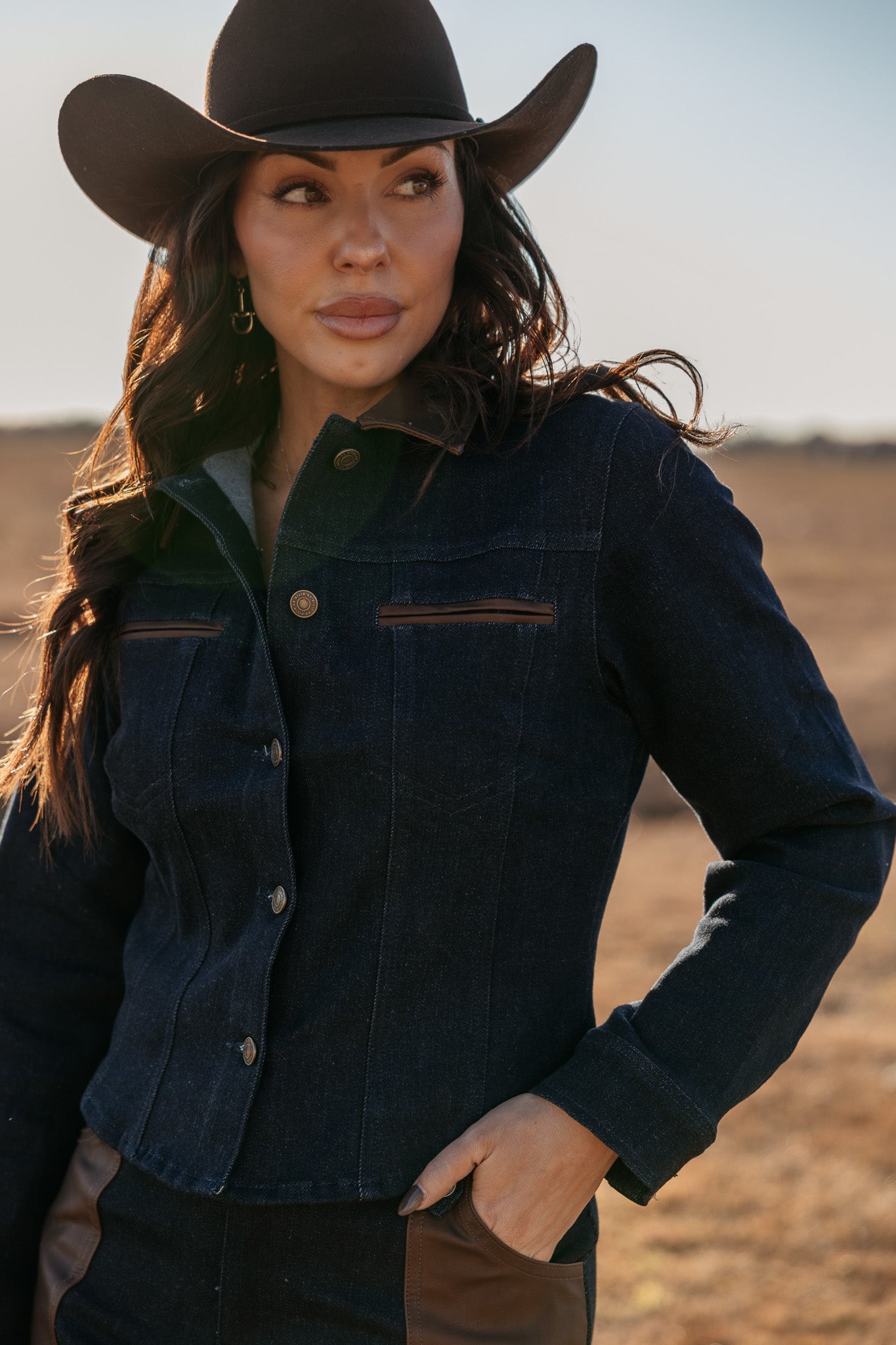Woman in a black cowboy hat and denim jacket with leather accents, western boho style outdoors