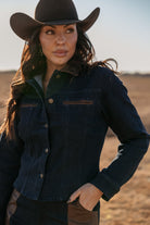 Woman in a black cowboy hat and denim jacket with leather accents, western boho style outdoors