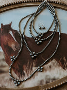 Western boho layered silver necklace and dangle earrings on horse-themed tray