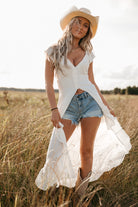 Woman in a white shirt and denim shorts standing in a field