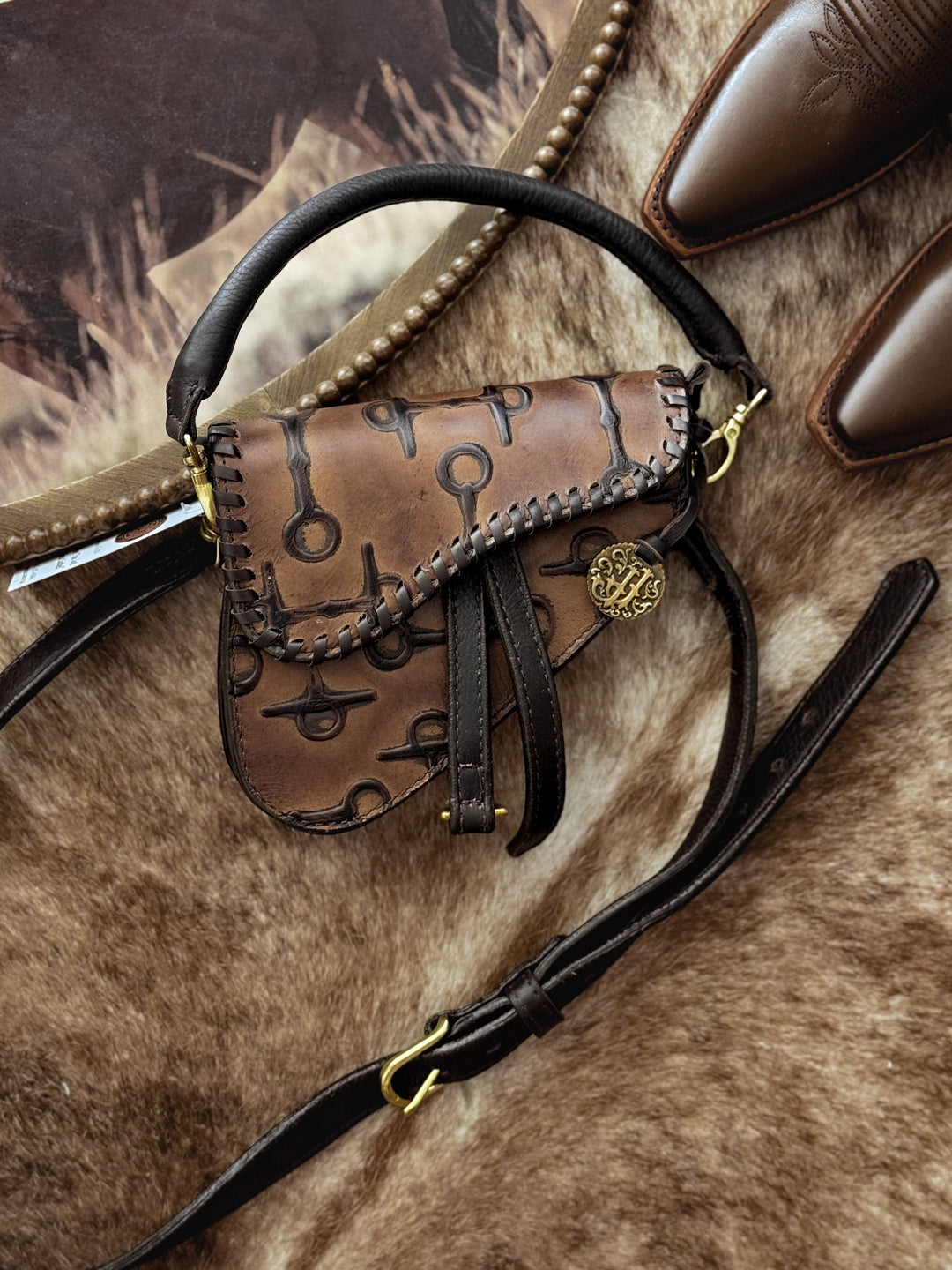 Caramel embossed leather saddle-style purse with snaffle-bit pattern and gold hardware.