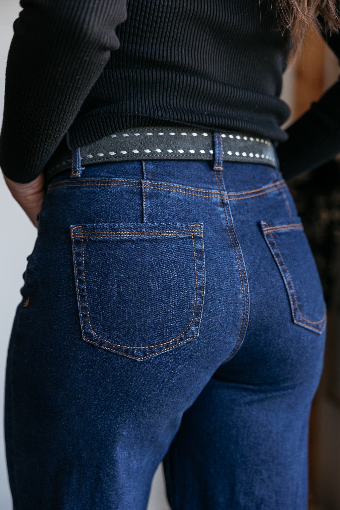 Close-up of woman wearing high-waisted blue denim jeans with a studded western belt