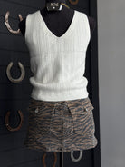 White knitted vest on a mannequin with a zebra print skirt against a dark background.