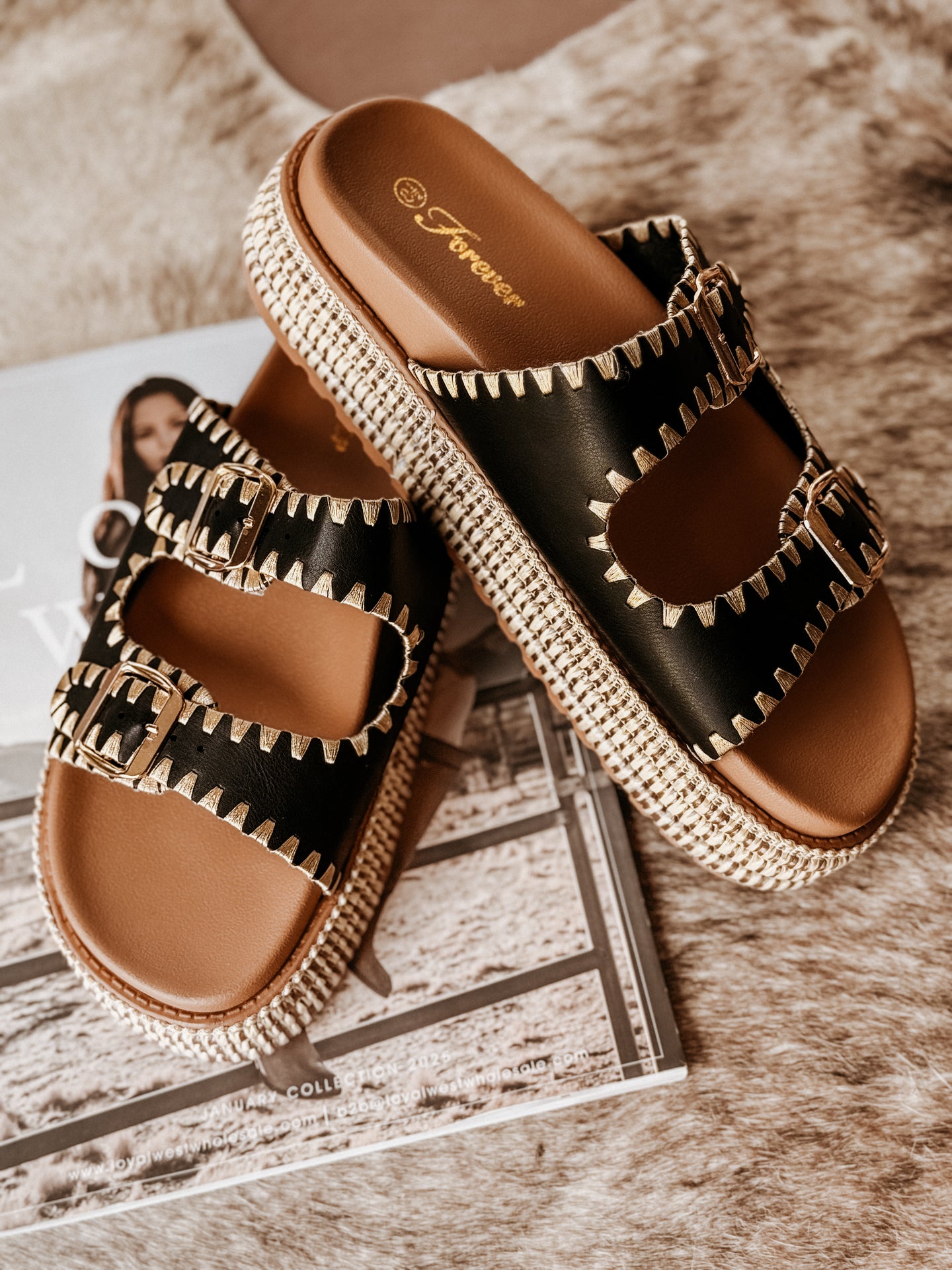 Black platform sandals featuring two stitched buckle straps with gold adjustable hardware, a braided raffia-style platform, textured sole for added grip, and a soft cushioned insole for comfort.