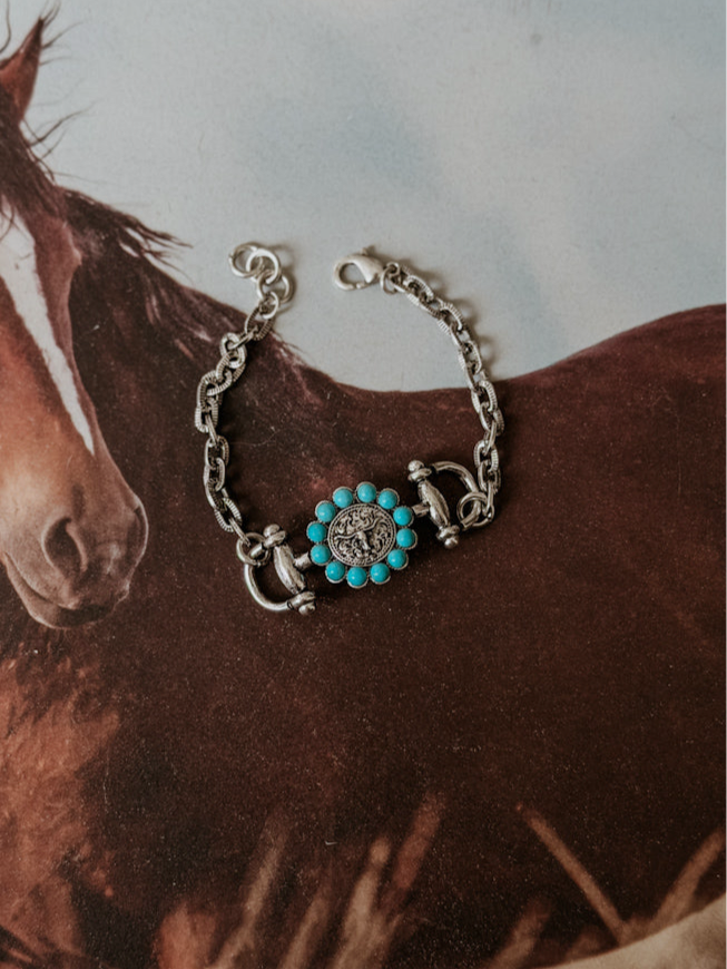 Thunderbird pendant chain necklace displayed on wooden slab with serape fabric underneath - The Wild J