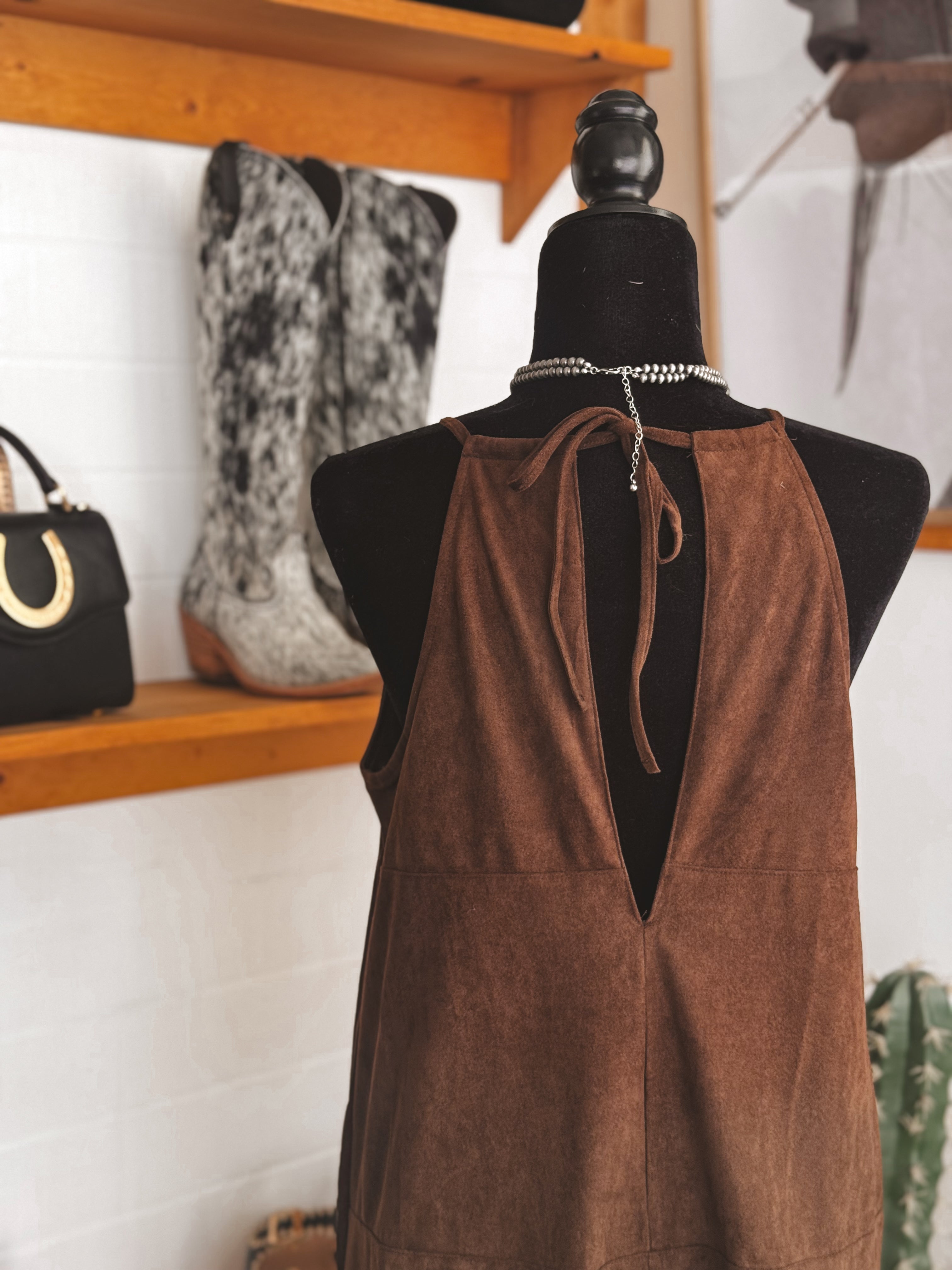 Brown suede western dress on mannequin, cowgirl boots and western bag in boutique setting
