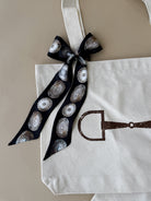 Thunderbird pendant chain necklace displayed on wooden slab with serape fabric underneath - The Wild J