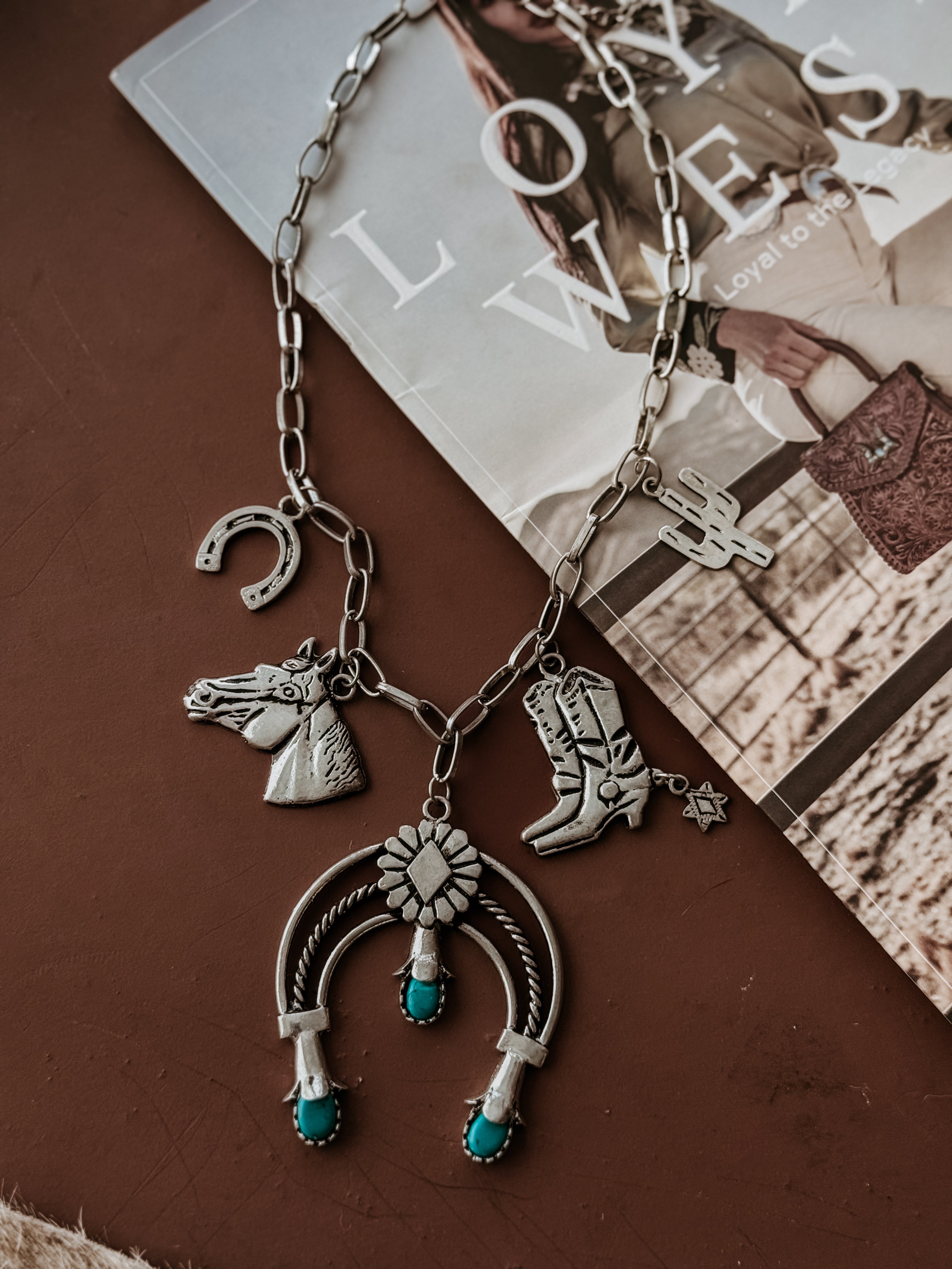 Thunderbird pendant chain necklace displayed on wooden slab with serape fabric underneath - The Wild J