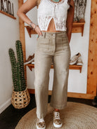 Woman wearing a white lace crop top and khaki wide-leg pants in a western boho boutique setting.