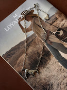 Thunderbird pendant chain necklace displayed on wooden slab with serape fabric underneath - The Wild J