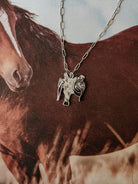 Western cowgirl necklace with horse and saddle pendant on horse background