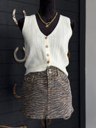 Mannequin wearing a white knitted vest over a zebra print skirt with a gold necklace.