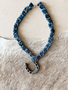 Western boho denim choker necklace with metal horseshoe pendant on cowhide background