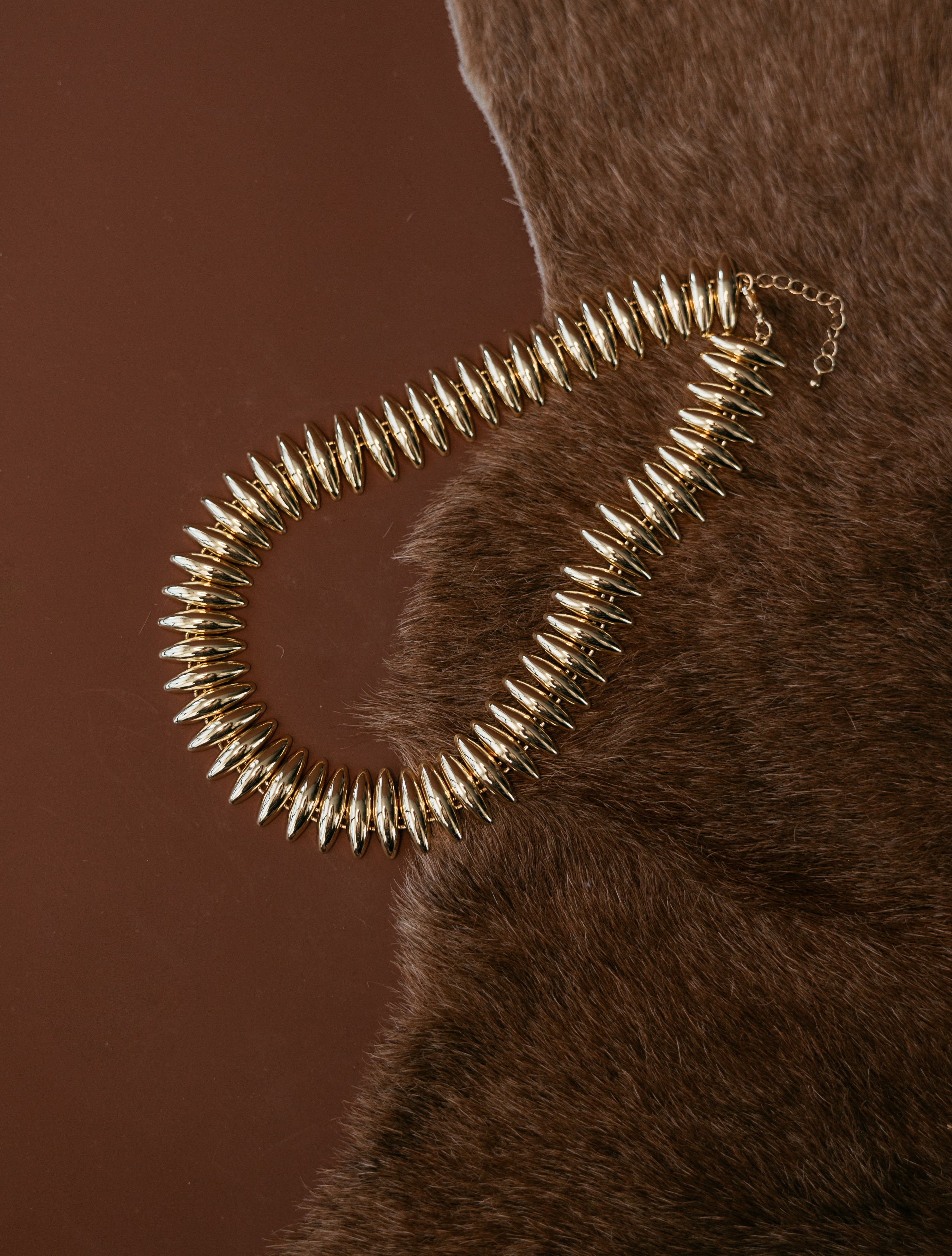 Thunderbird pendant chain necklace displayed on wooden slab with serape fabric underneath - The Wild J