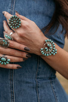 Woman wearing multiple turquoise western rings and bracelet with denim dress