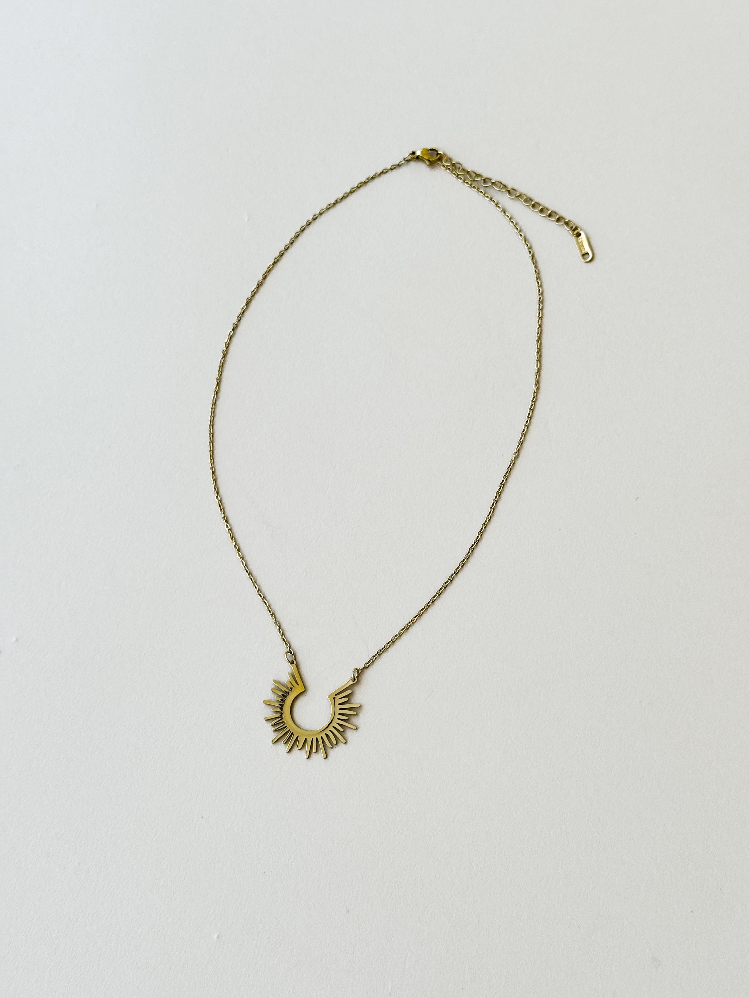 Thunderbird pendant chain necklace displayed on wooden slab with serape fabric underneath - The Wild J