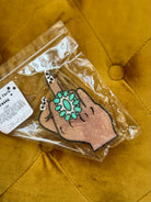 Western boho hand-shaped air freshener with turquoise ring on yellow tufted fabric.