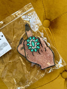 Western boho middle finger hand sticker with turquoise ring on mustard fabric background
