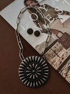 Thunderbird pendant chain necklace displayed on wooden slab with serape fabric underneath - The Wild J