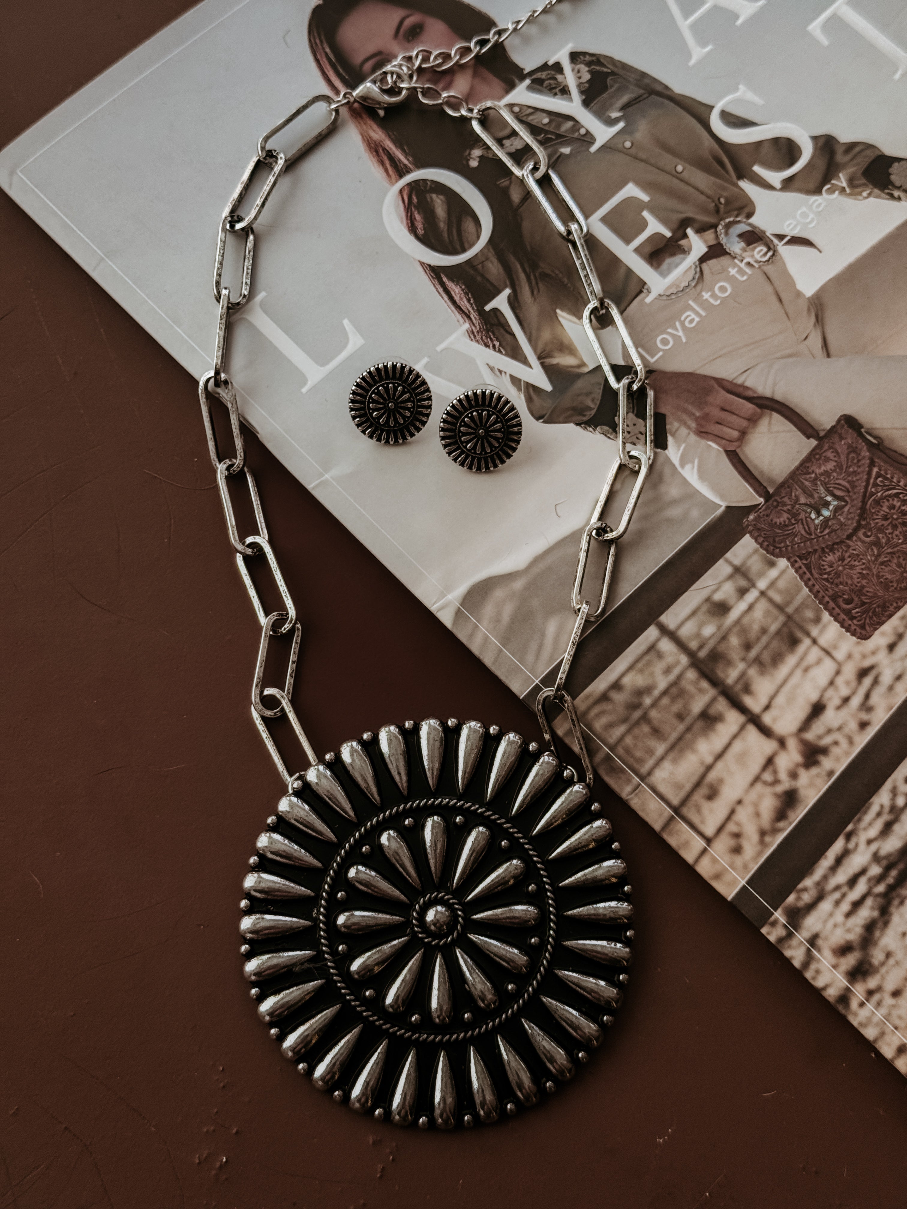 Thunderbird pendant chain necklace displayed on wooden slab with serape fabric underneath - The Wild J