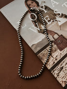 Silver western bead necklace on brown table with cowgirl magazine