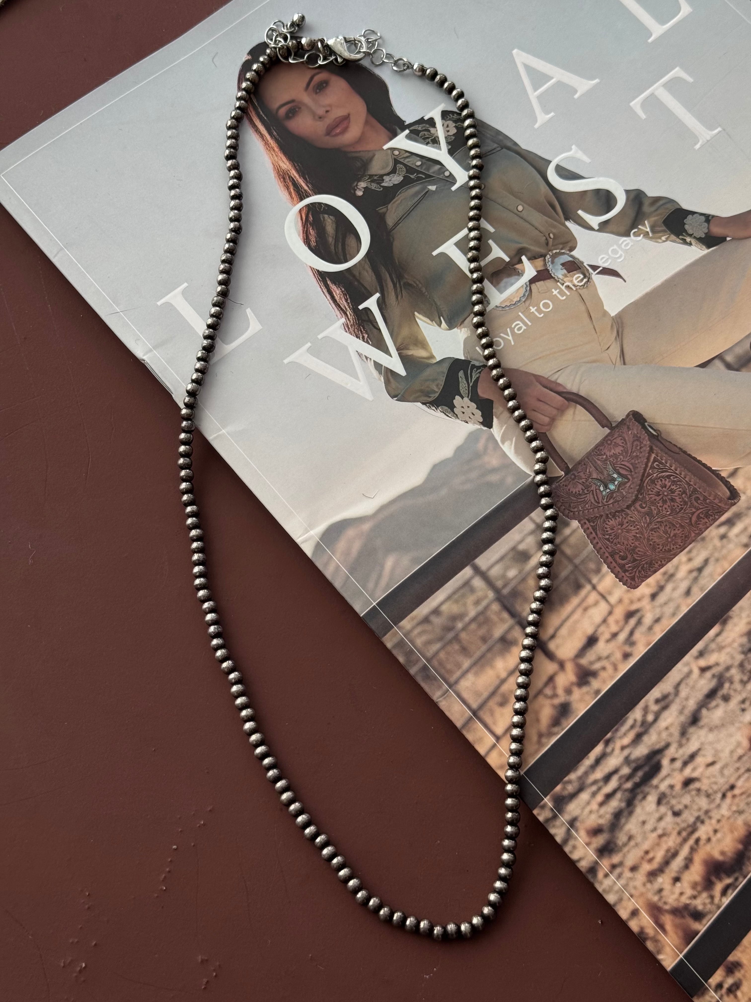 Thunderbird pendant chain necklace displayed on wooden slab with serape fabric underneath - The Wild J