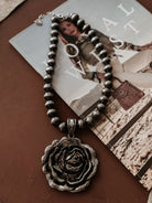 Thunderbird pendant chain necklace displayed on wooden slab with serape fabric underneath - The Wild J