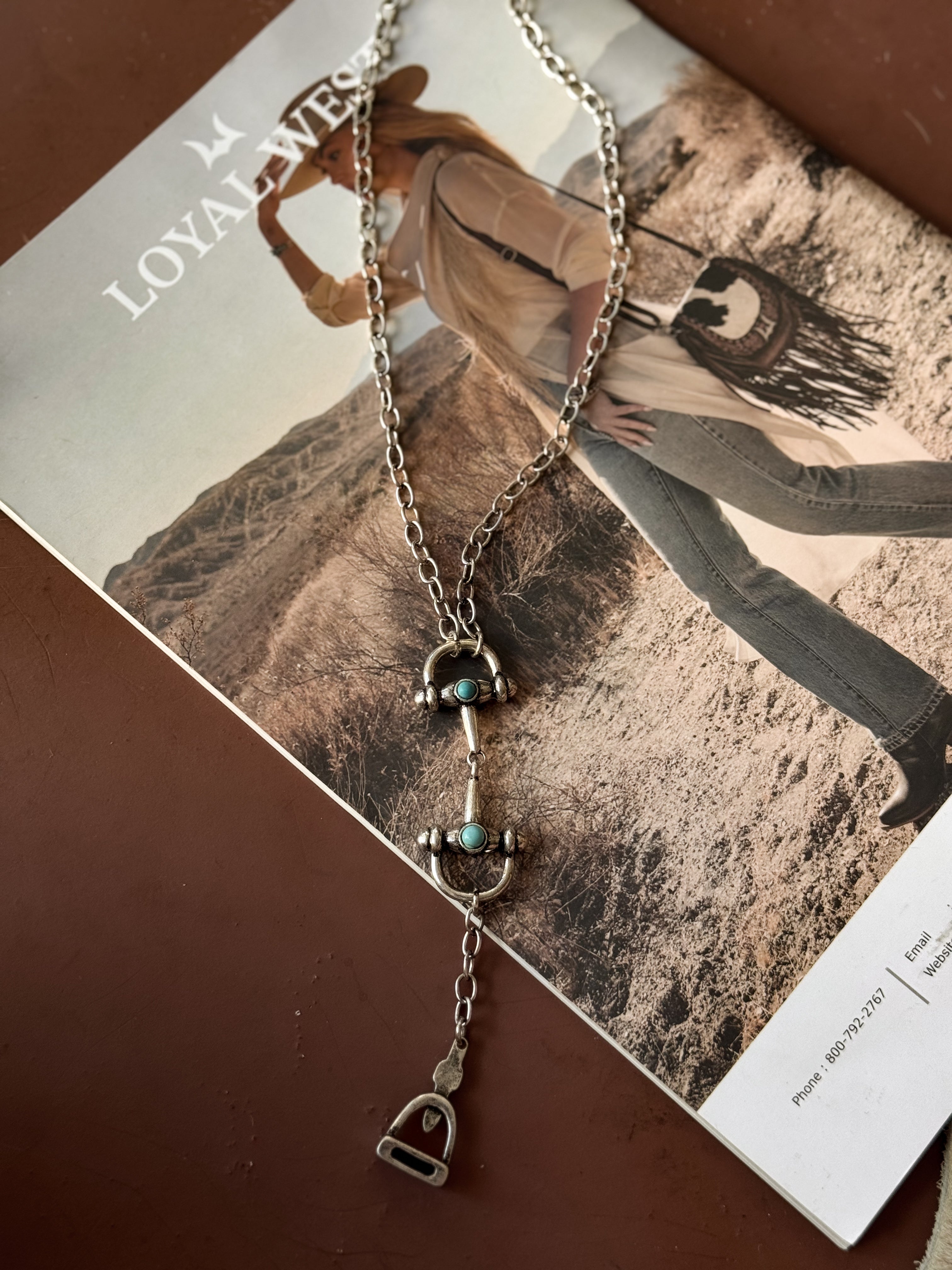 Thunderbird pendant chain necklace displayed on wooden slab with serape fabric underneath - The Wild J