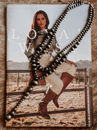 Thunderbird pendant chain necklace displayed on wooden slab with serape fabric underneath - The Wild J