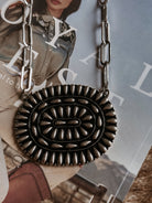 Thunderbird pendant chain necklace displayed on wooden slab with serape fabric underneath - The Wild J