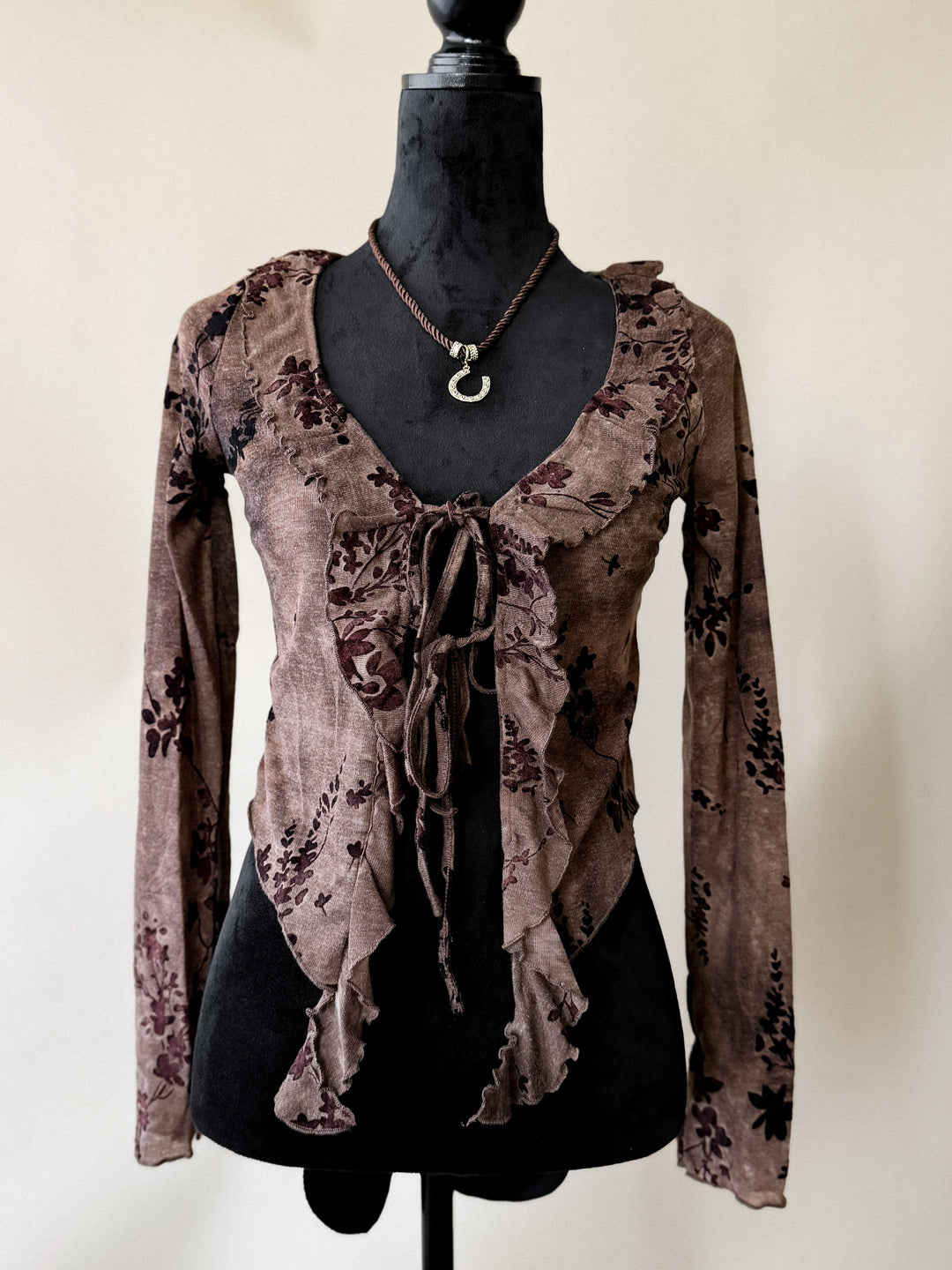 Brown floral blouse on a mannequin against a plain background