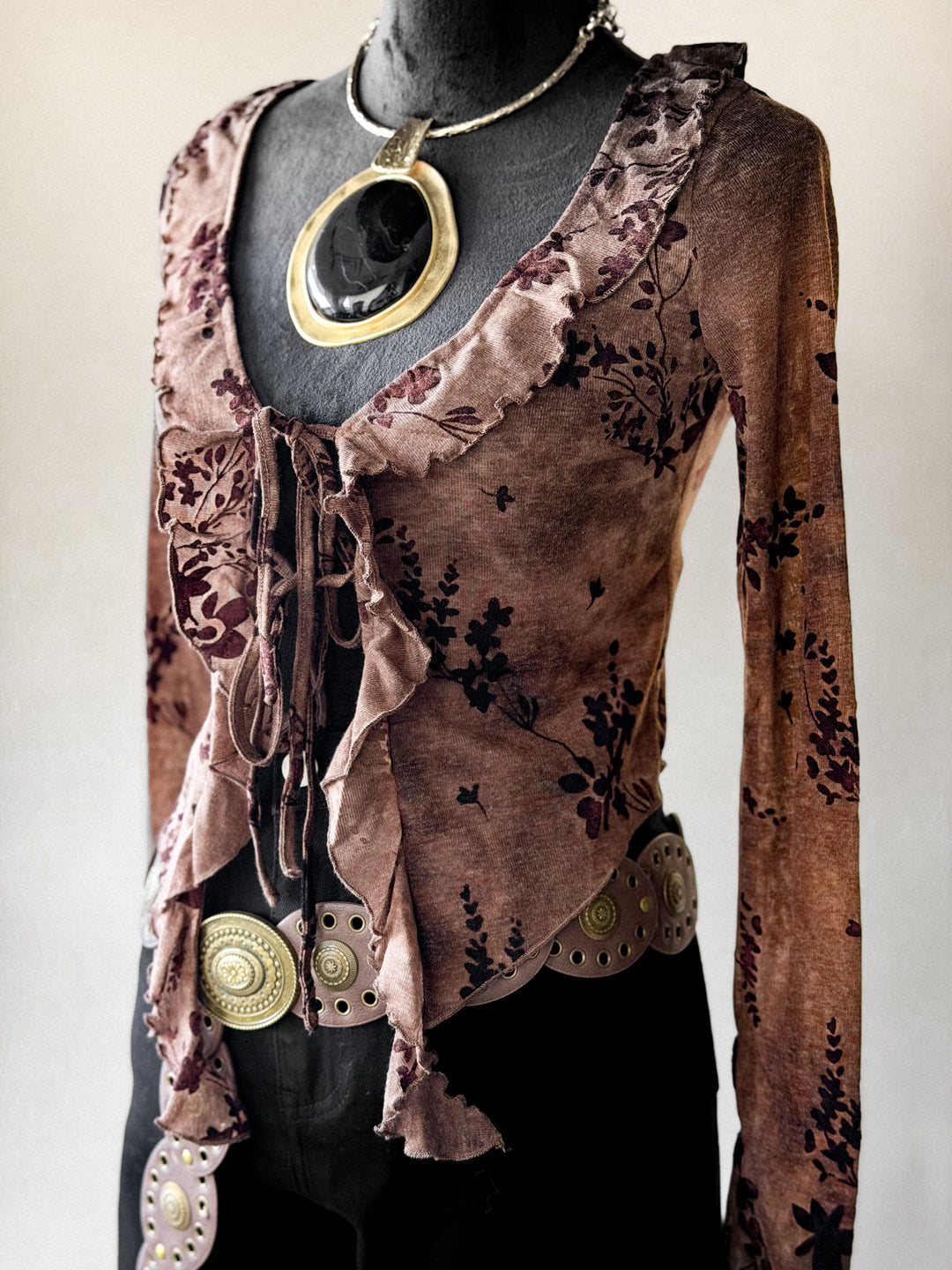 Brown floral-patterned blouse with decorative buttons on a mannequin against a white background
