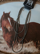 Thunderbird pendant chain necklace displayed on wooden slab with serape fabric underneath - The Wild J