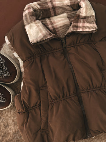 Brown winter coat with plaid lining and matching boots on a brown background