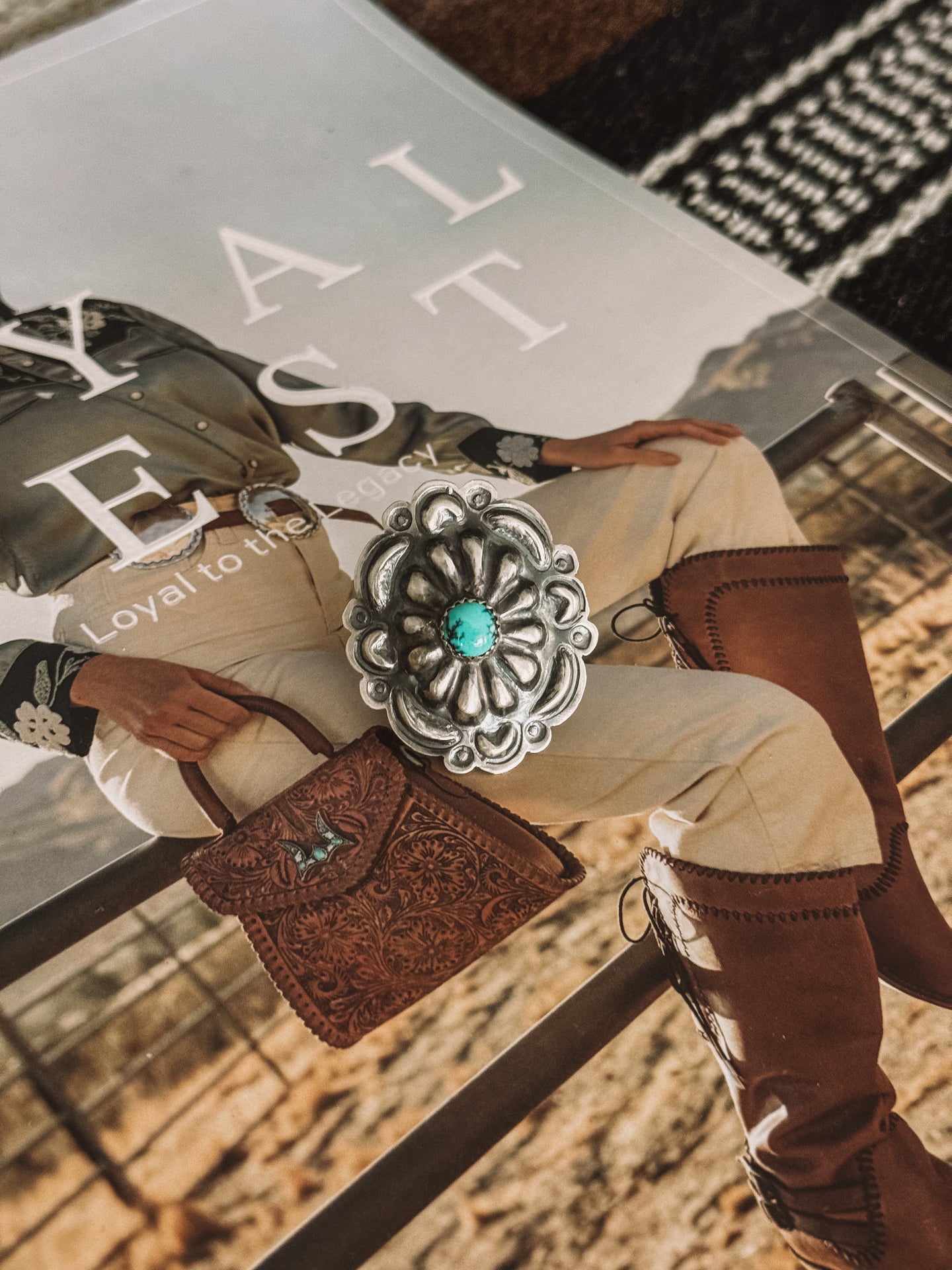 A Navajo Concho Ring with a turquoise stone at its center, displayed on a person's finger.