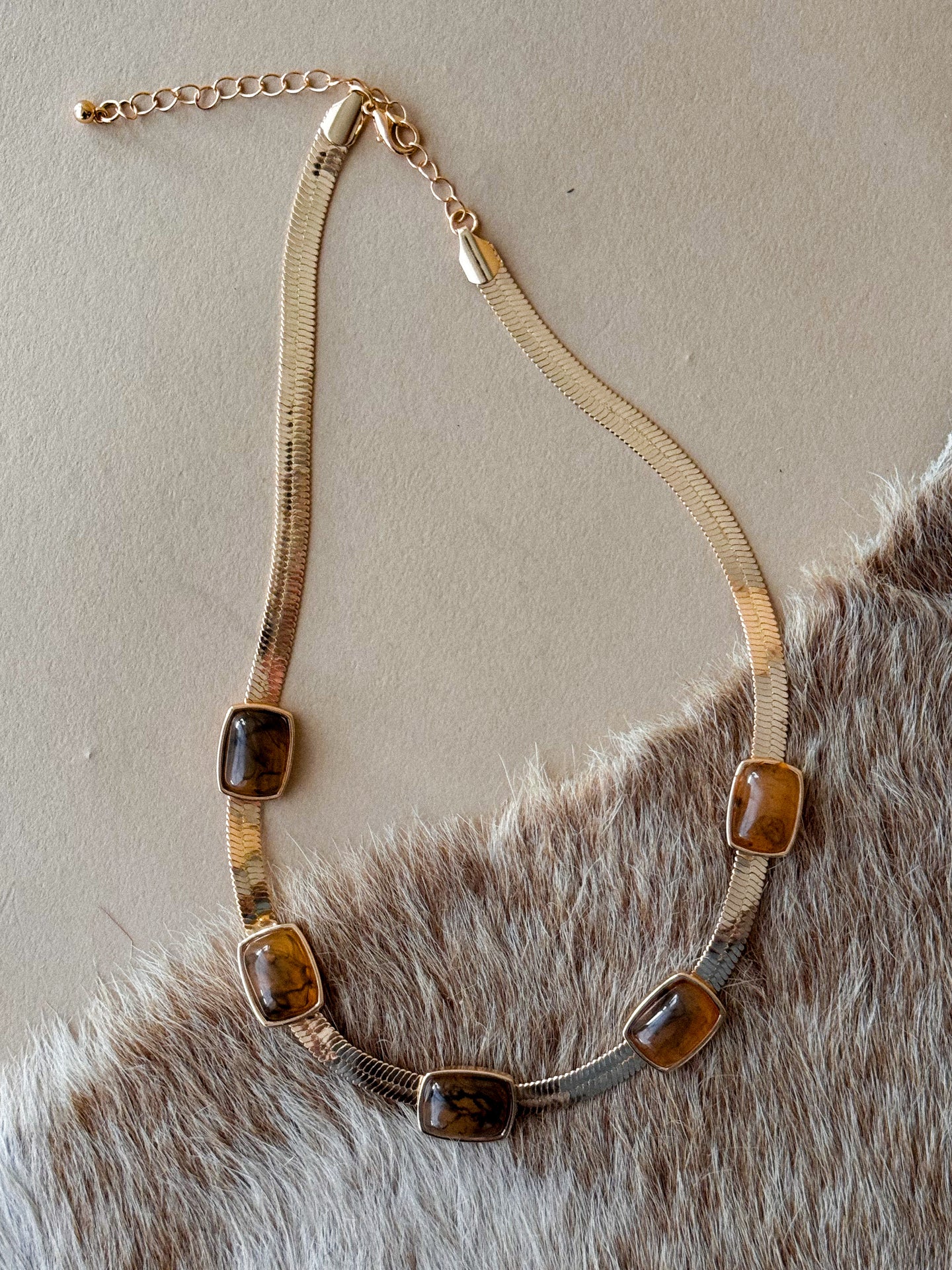 Gold herringbone-style chain necklace with veined brown stones