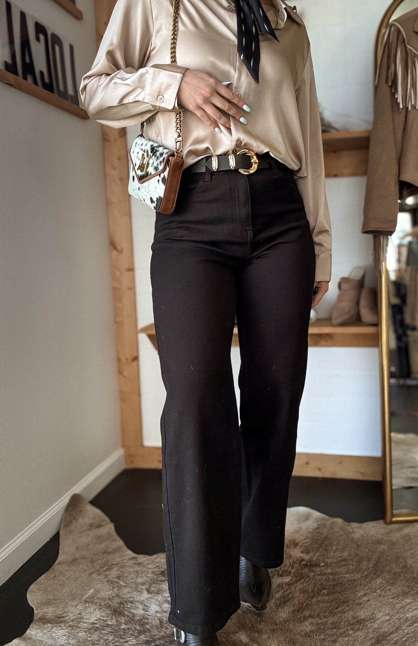 Model wearing high-rise wide leg black jeans with western blouse and boots.