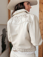 Woman in cream western embroidered leather jacket and cowboy hat, boho cowgirl style