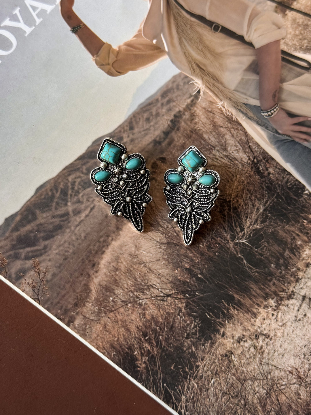 Pair of earrings with turquoise stones on a textured surface