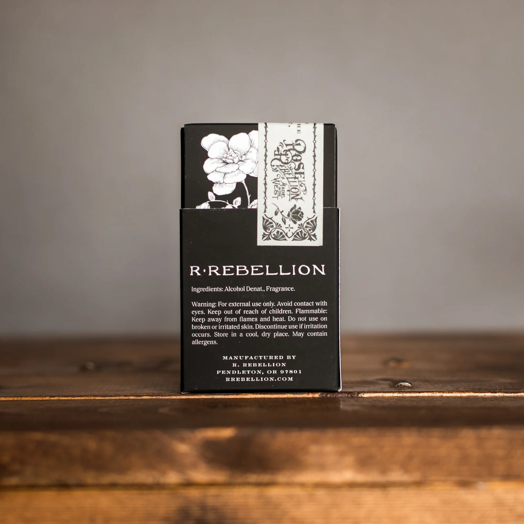 Black packaging with floral design and 'R-Rebellion' branding on a wooden surface.