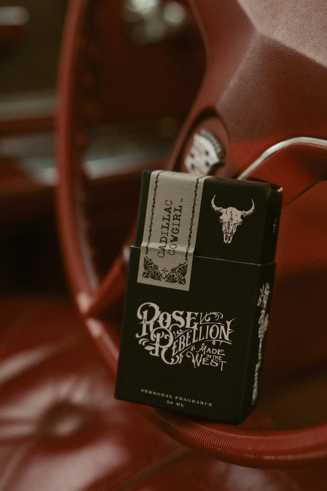cadillac cowgirl scent packaging against red cadillac