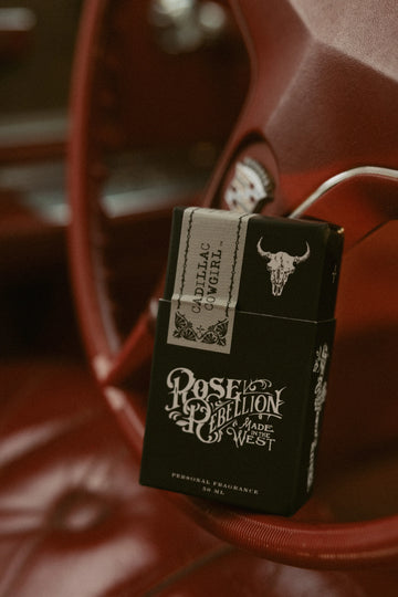 cadillac cowgirl scent packaging against red cadillac