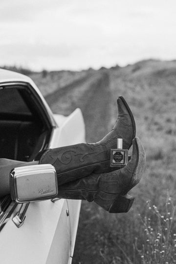 cowboy boots holding cadillar cowgirl perfume