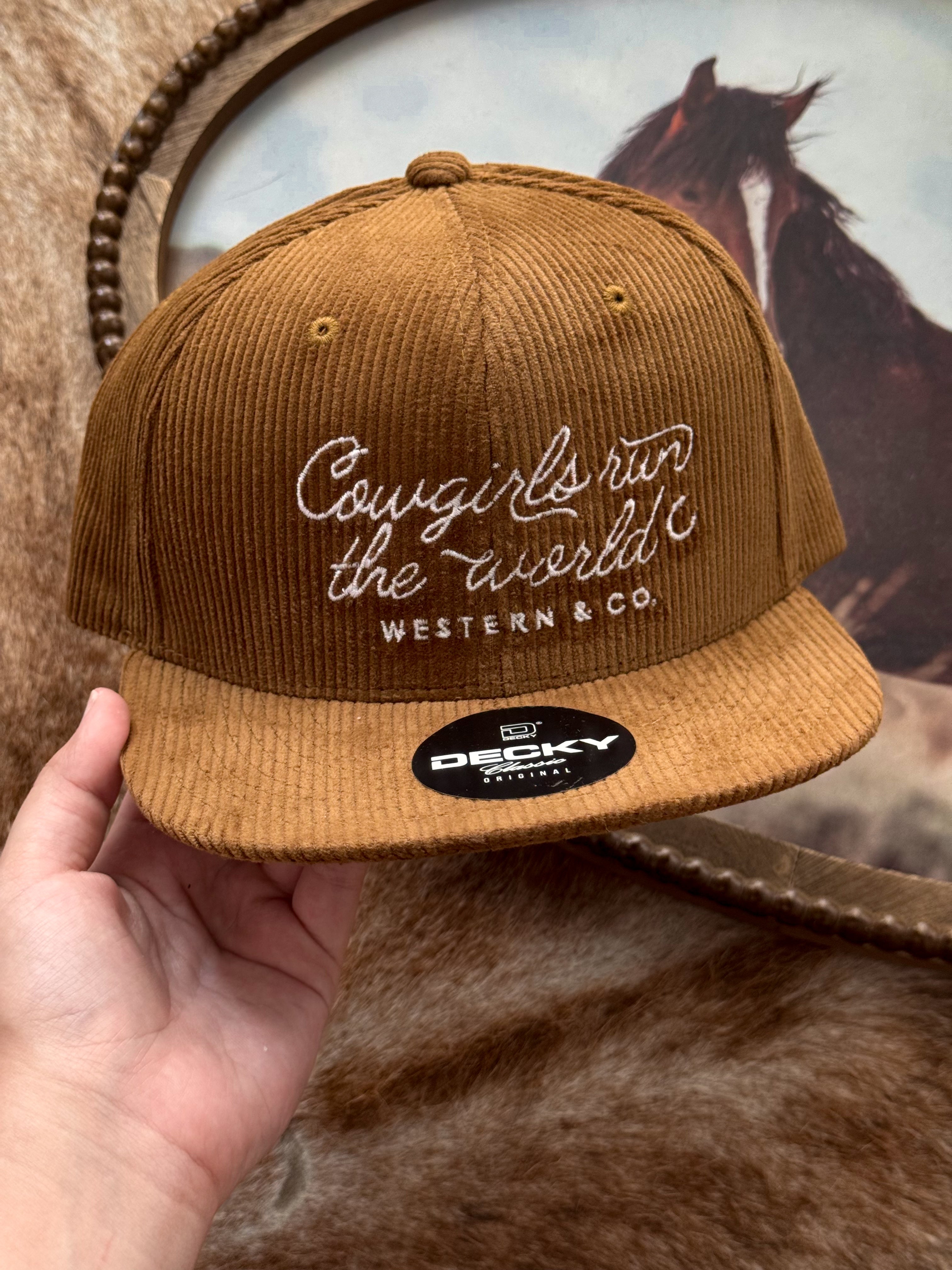 Brown corduroy western baseball hat with 'Cowgirls run the world' embroidery, held by hand.