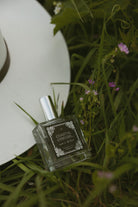 Perfume bottle labeled 'Coastal Cowgirl' on grass with flowers